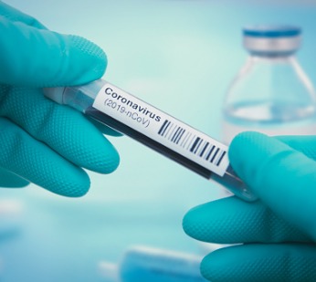 gloved hands holding a vial labeled coronavirus